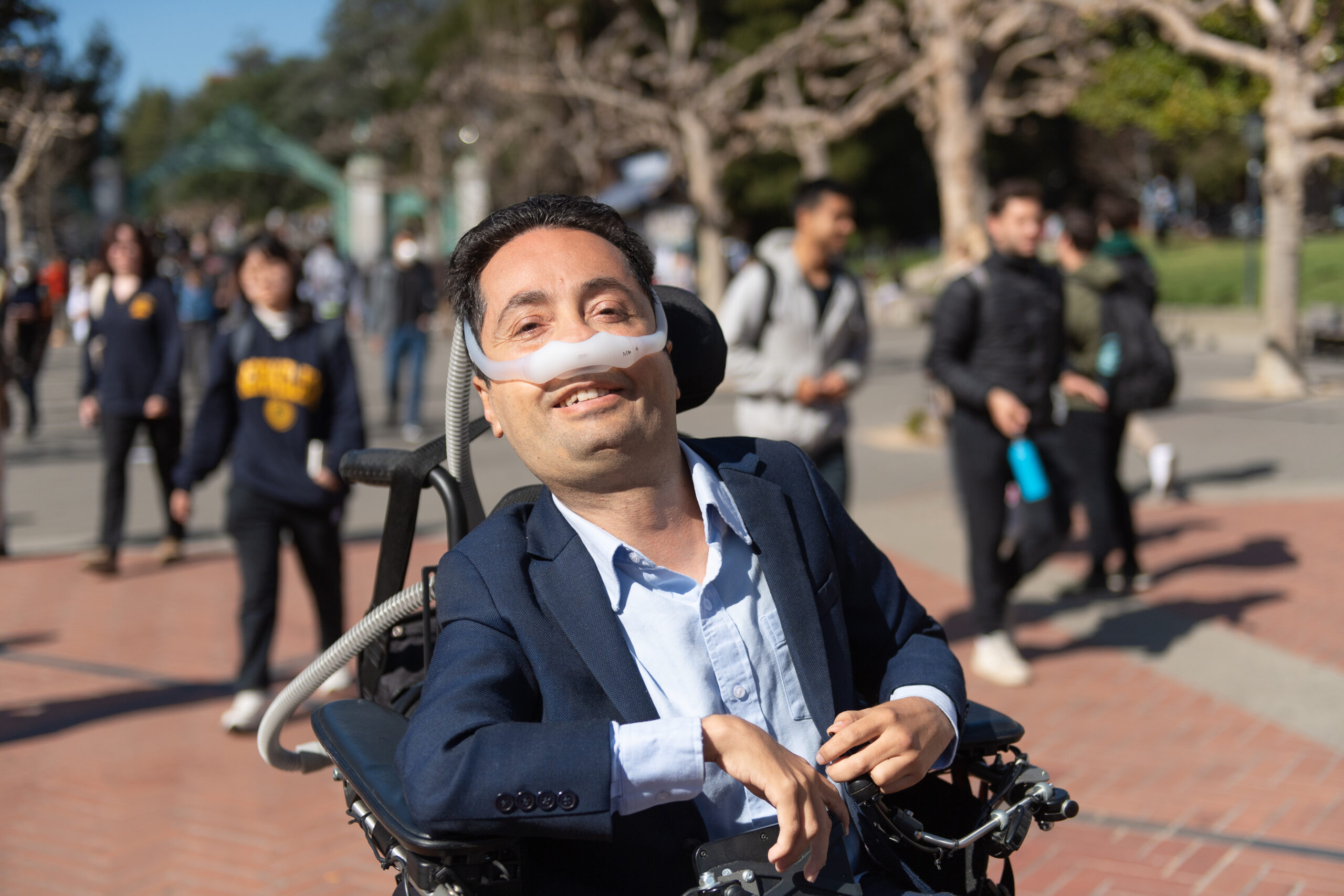 Person using a wheelchair smiling while navigating an accessible city street, surrounded by inclusive infrastructure and diverse community members.