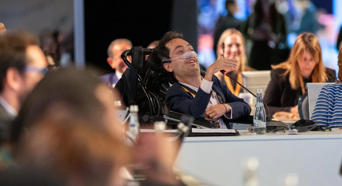 Victor Pineda speaking to a group of diverse advocates during an accessibility workshop, with participants listening attentively.